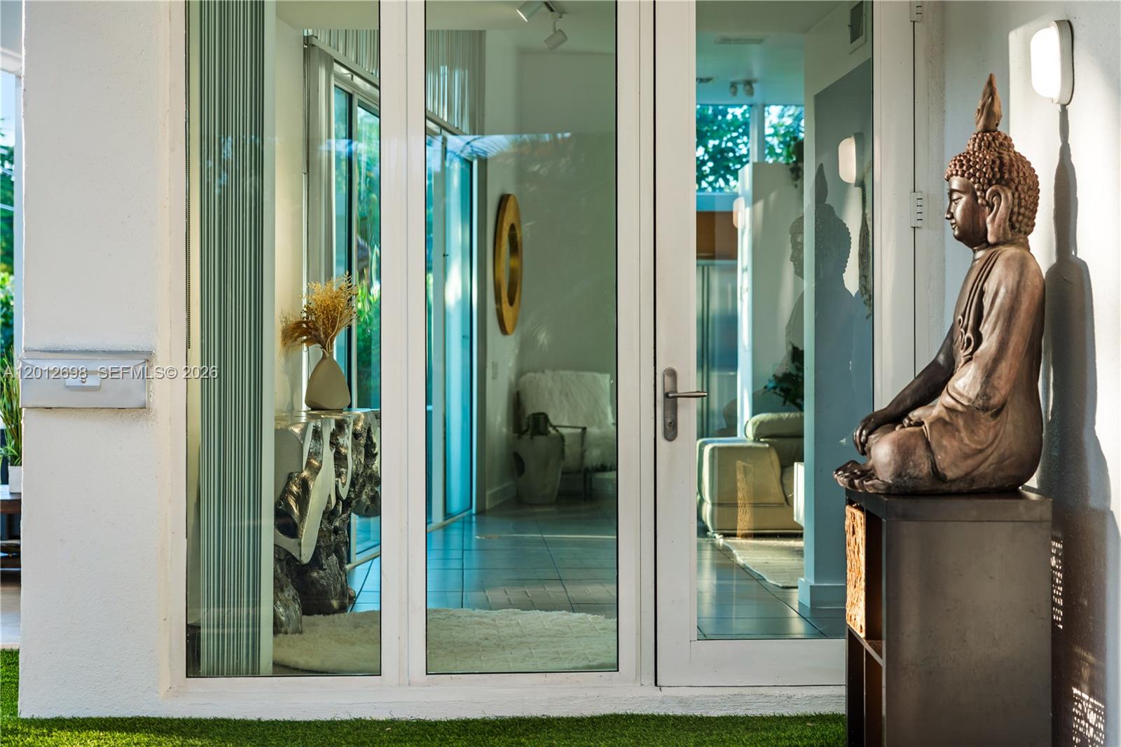 A Buddha statue sits on a pedestal outside a glass door leading into a home — 1898 SW 17th St, Miami FL 33145, MIAMI, FL
