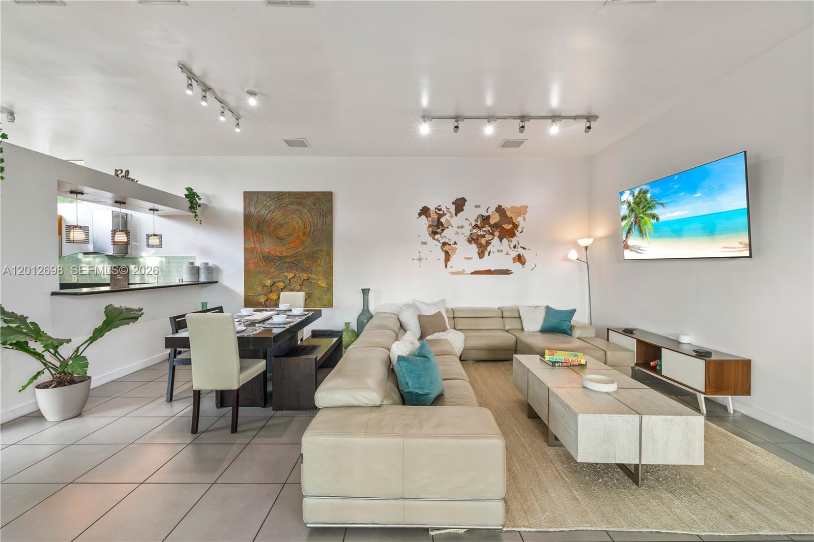 A modern living and dining area features a large sectional sofa, wooden table, and wall-mounted television — 1898 SW 17th St, Miami FL 33145, MIAMI, FL
