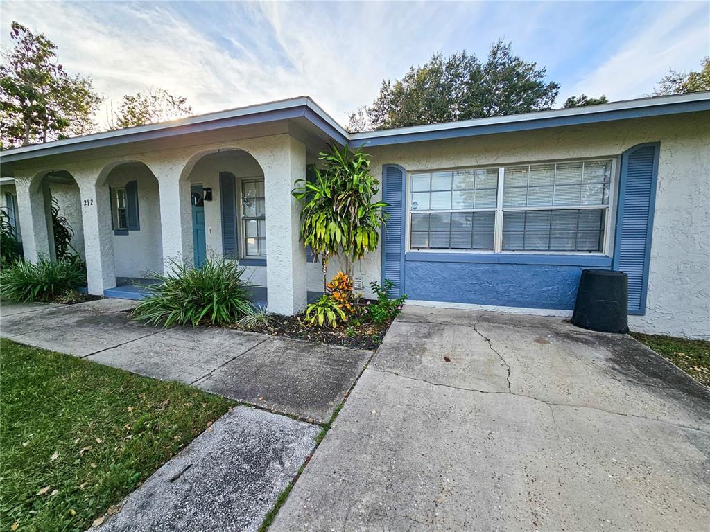A single-story house exterior features a covered arched entryway, blue shutters, and a concrete driveway — 212 S CORTEZ AVENUE, WINTER SPRINGS, FL