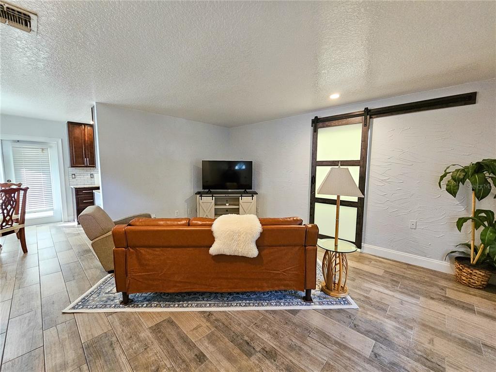 A living room features a leather sofa, a television on a stand, and a sliding door — 212 S CORTEZ AVENUE, WINTER SPRINGS, FL
