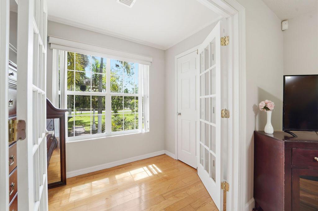 A room with hardwood floors, a large window, and white French doors — 6929 N 120th Ave Avenue N, FL 33412, FL