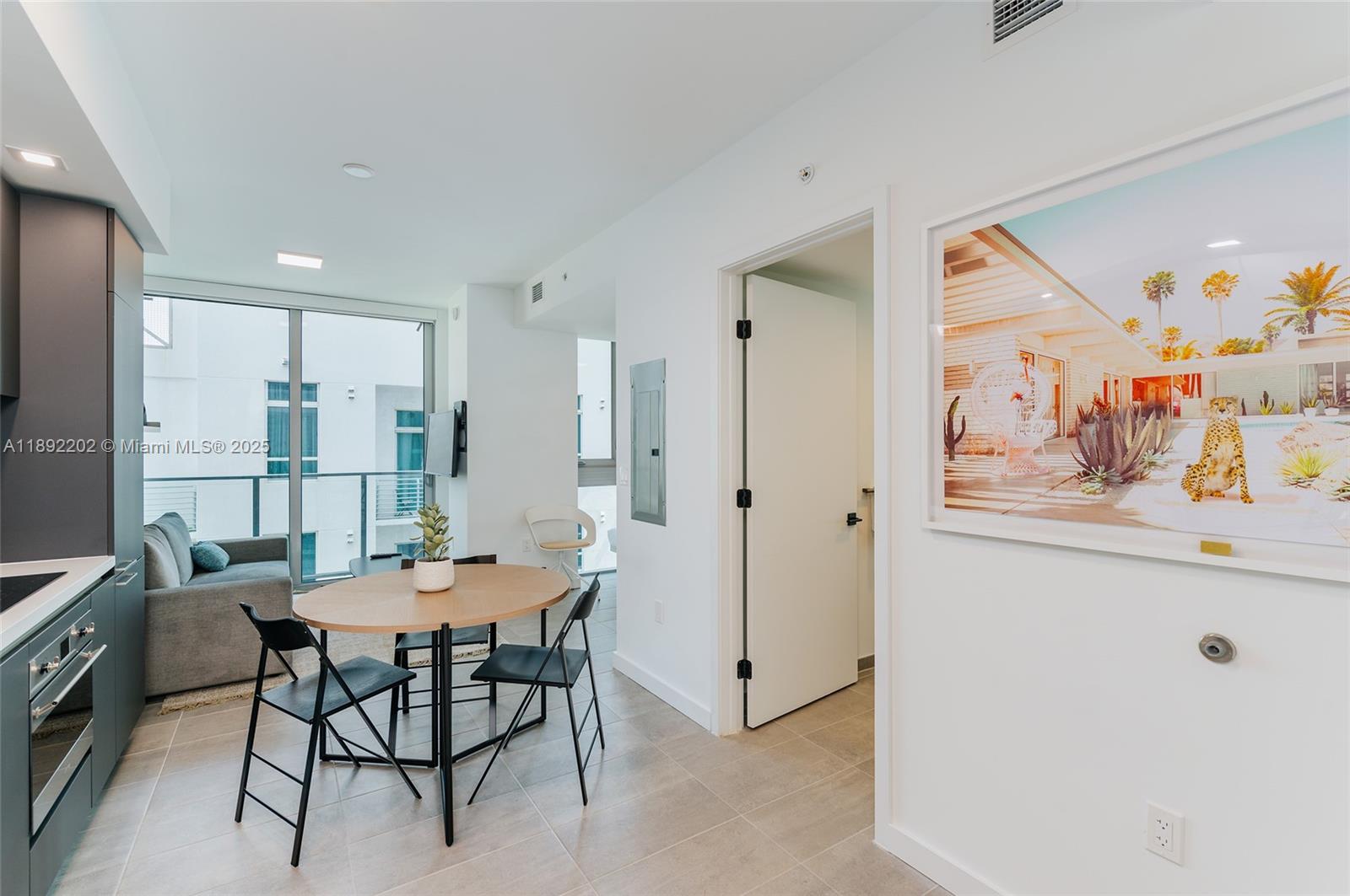 A modern kitchen and dining area features a round table, dark cabinetry, and tile flooring — 227 NE 2nd St # 2508, Miami FL 33132, MIAMI, FL