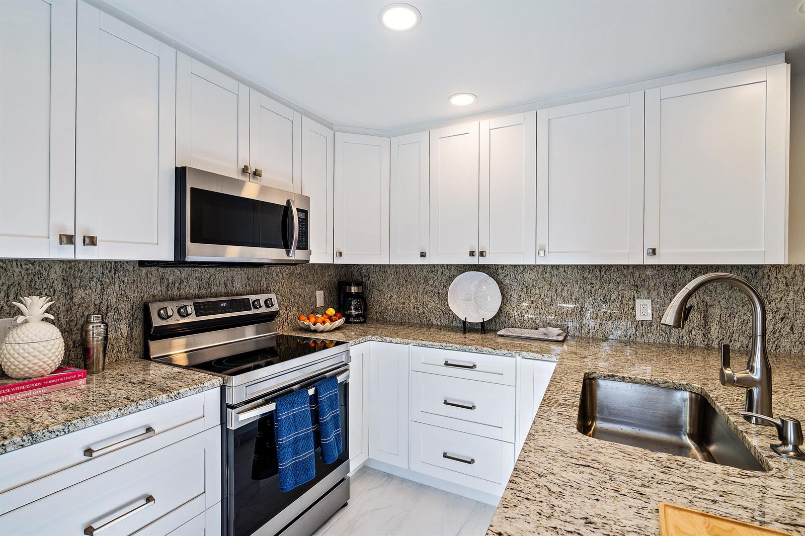 A kitchen features white cabinets, granite countertops, stainless steel appliances, and a stainless steel sink — 2316 23rd Court, Jupiter FL 33477, JUPITER, FL