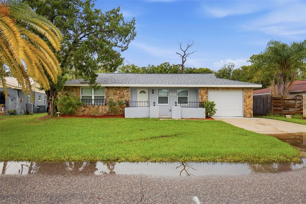 A single-story house with a stone facade, gray siding, and a front-facing attached garage — 8531 HORIZON LANE, HUDSON, FL