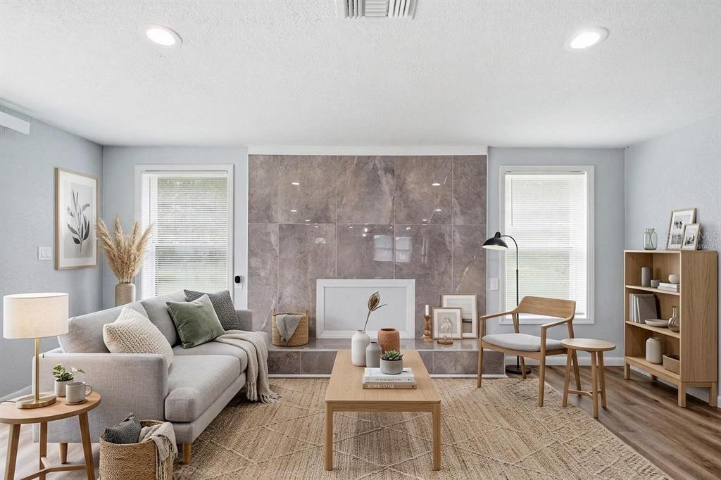 A living room features a large gray tiled fireplace, a light gray sofa, and wood furniture — 8531 HORIZON LANE, HUDSON, FL