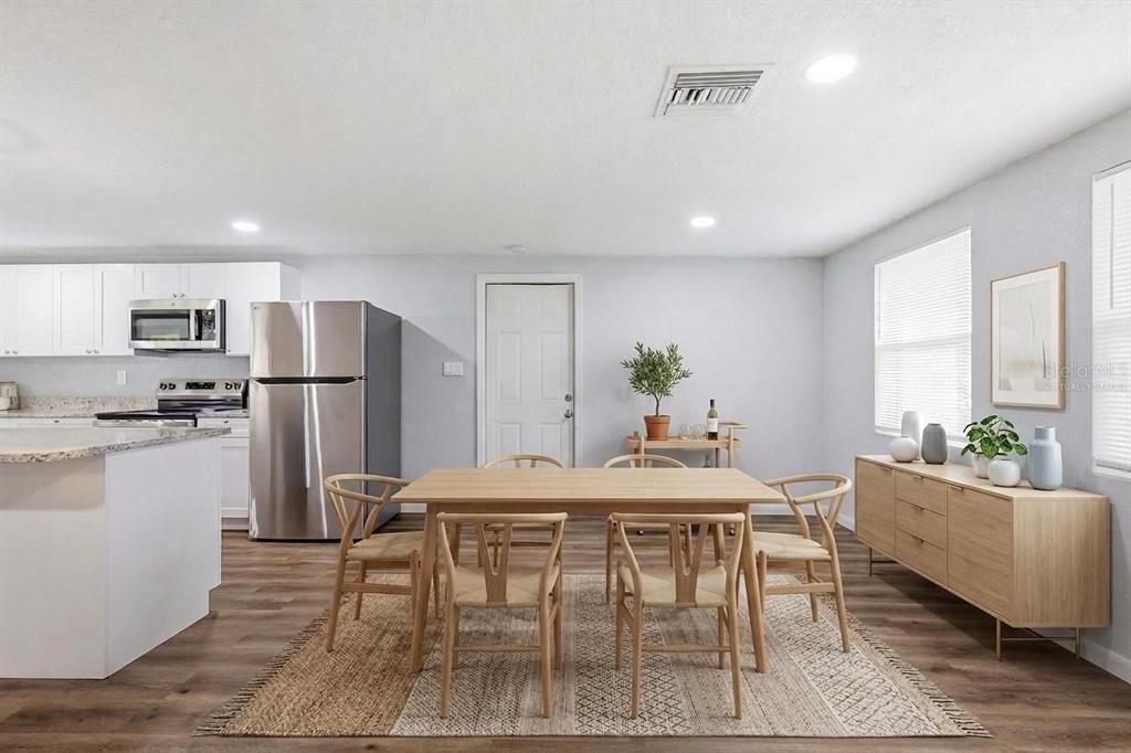 A dining area features a wooden table, six chairs, a sideboard, and a kitchen nearby — 8531 HORIZON LANE, HUDSON, FL