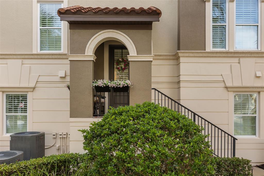The exterior of a multi-story home features a covered entryway with a tiled roof — 801 LOBELIA DRIVE, LAKE MARY, FL