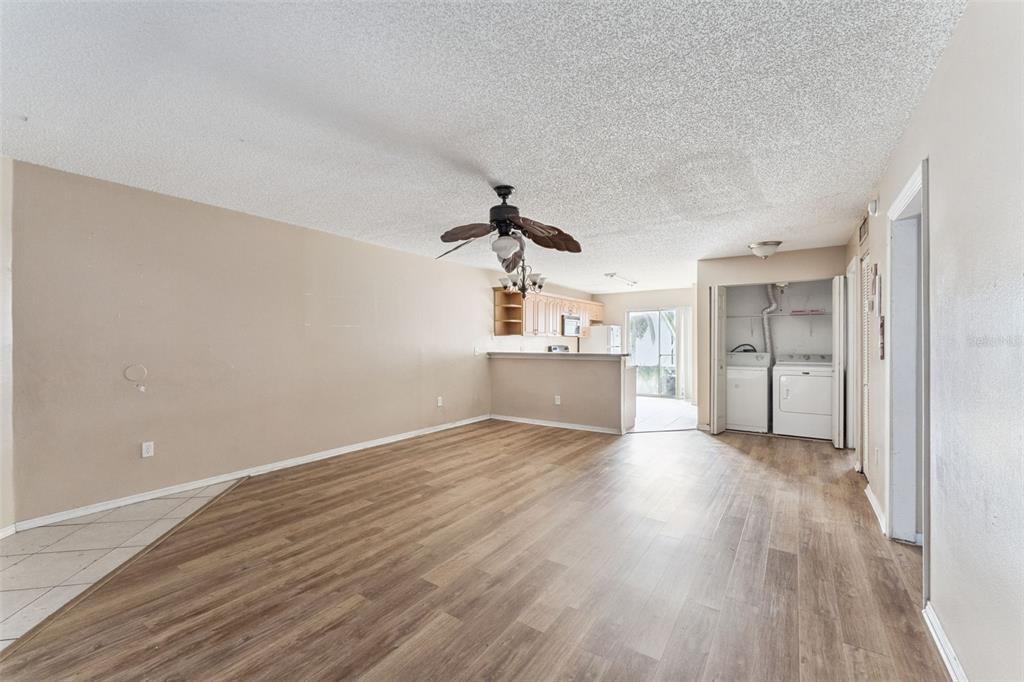 An open-concept living area features wood-look flooring, a ceiling fan, and a laundry closet — 3651 N GOLDENROD ROAD UNIT 110, WINTER PARK, FL