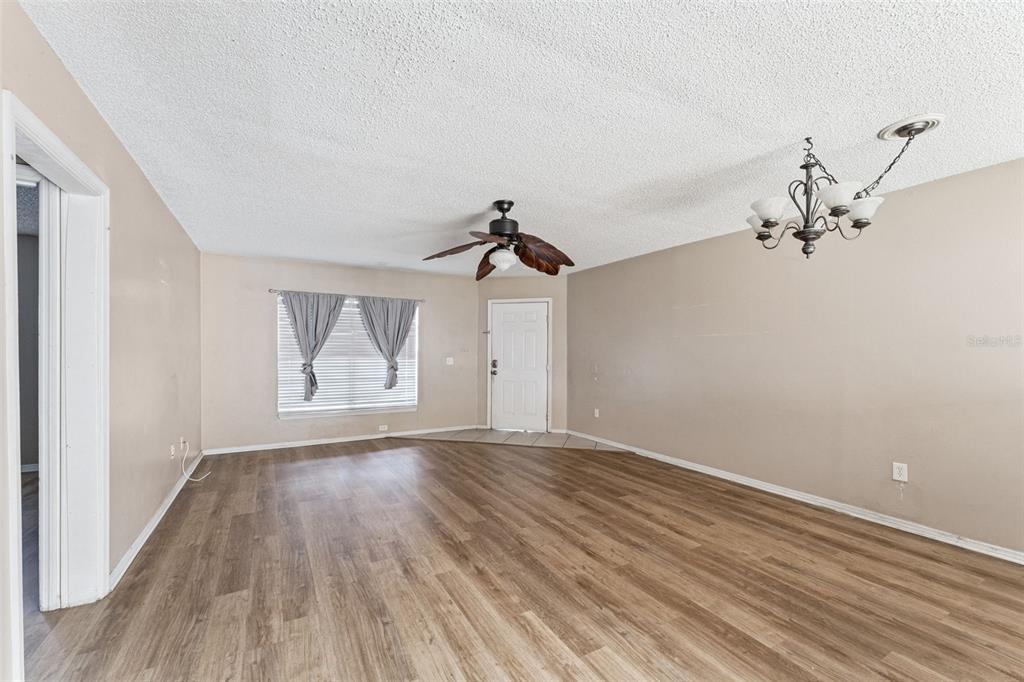 A living room with wood-look flooring, a ceiling fan, a chandelier, and a front door — 3651 N GOLDENROD ROAD UNIT 110, WINTER PARK, FL
