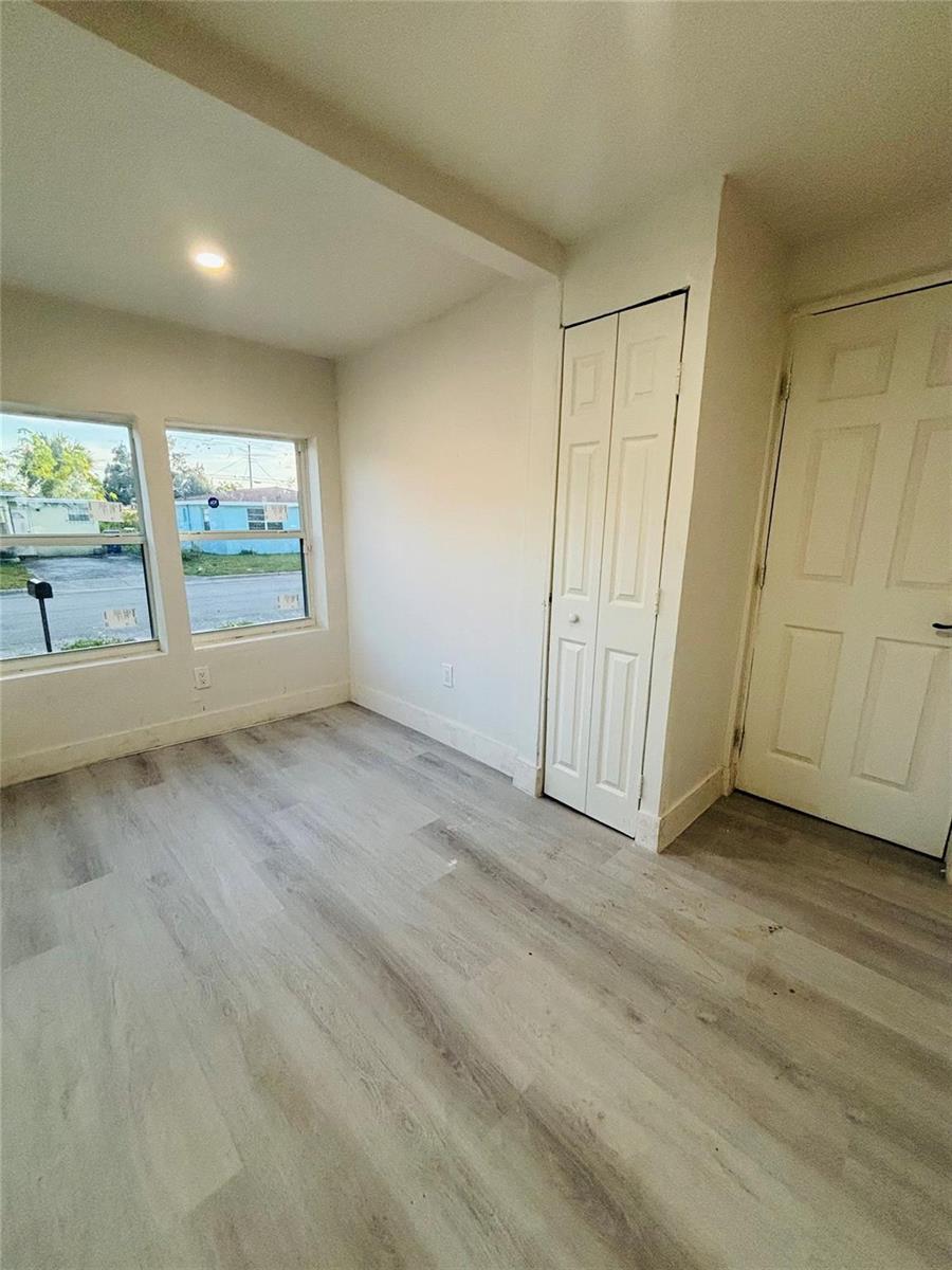 An empty room with light wood-look flooring, white walls, two windows, and a closet — 1116 W 32nd Street, Riviera Beach FL 33404, RIVIERA BEACH, FL