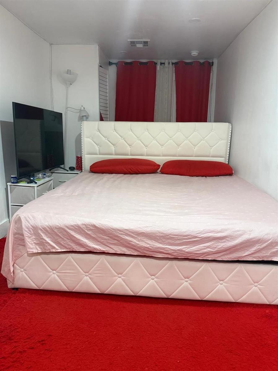 A bedroom features a white tufted bed frame, red pillows, and a red carpet — 1116 W 32nd Street, Riviera Beach FL 33404, RIVIERA BEACH, FL