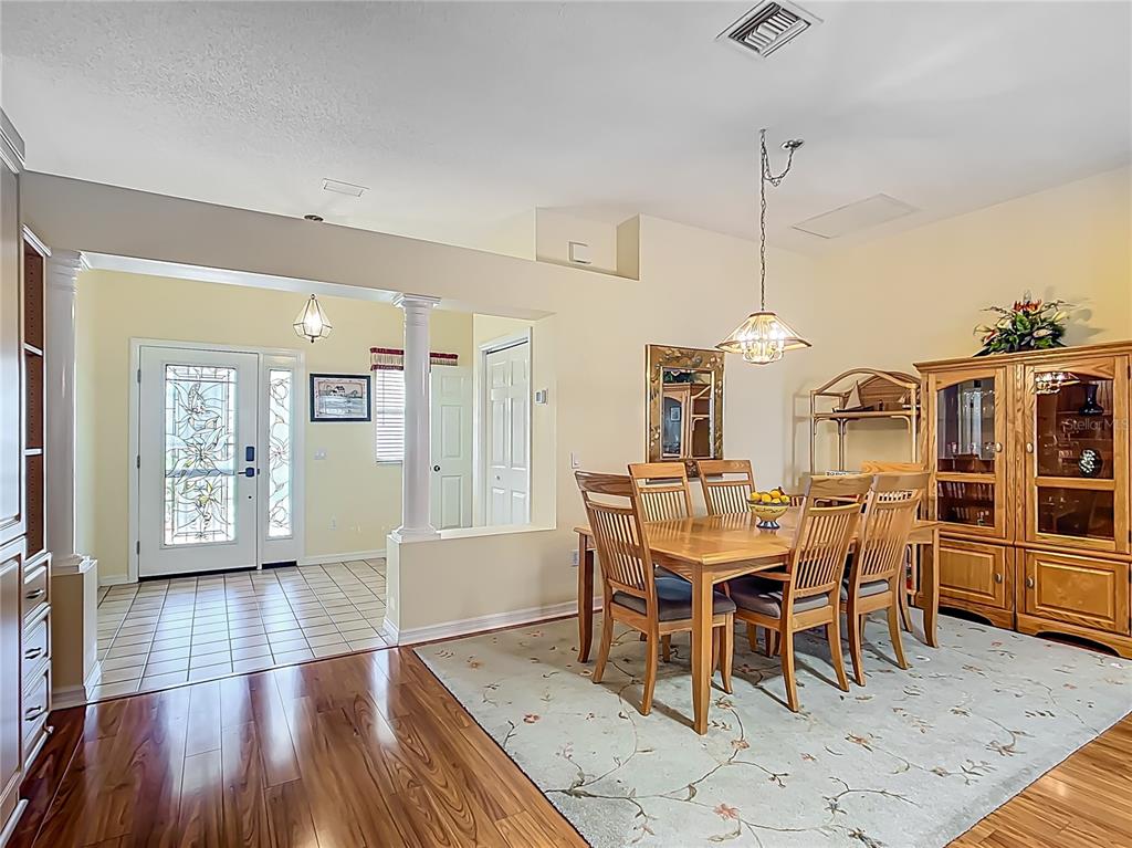 A dining room with a wooden table and chairs sits beside an entryway with tile — 208 DESOTA COURT, LADY LAKE, FL