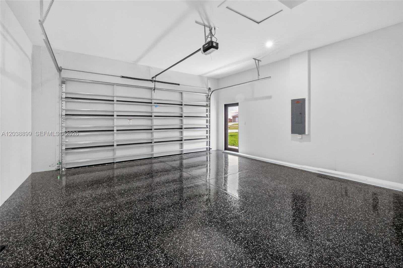 A garage with a black speckled epoxy floor, white walls, and a metal door frame — 2014 SW 8th PL, Cape Coral FL 33991, CAPE CORAL, FL