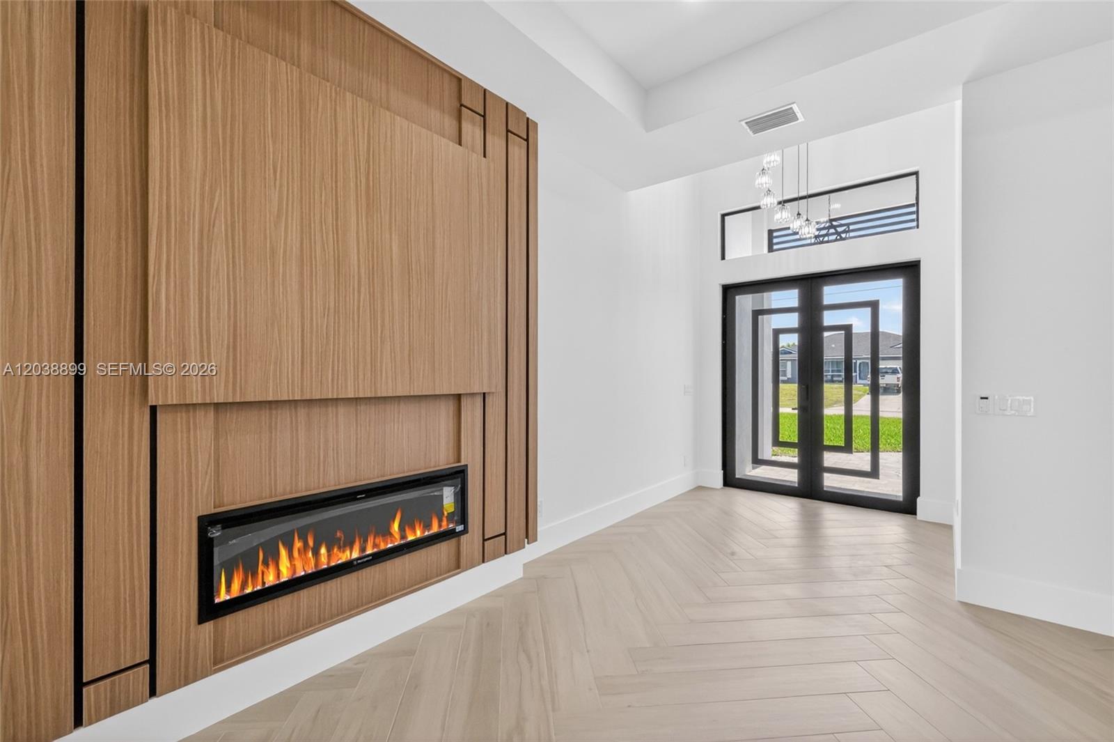 A modern entryway features a wood-paneled accent wall with a fireplace and herringbone flooring — 2014 SW 8th PL, Cape Coral FL 33991, CAPE CORAL, FL