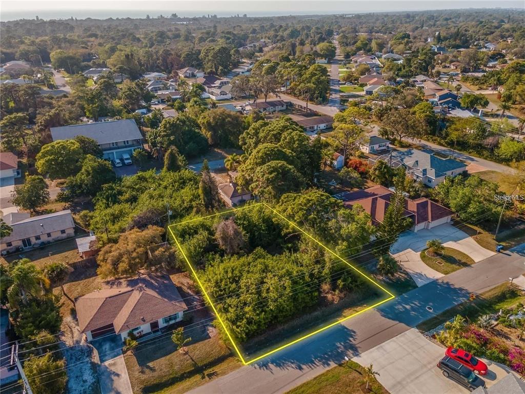 An aerial view shows a vacant, tree-covered residential lot outlined in yellow — OSPREY ROAD, VENICE, FL
