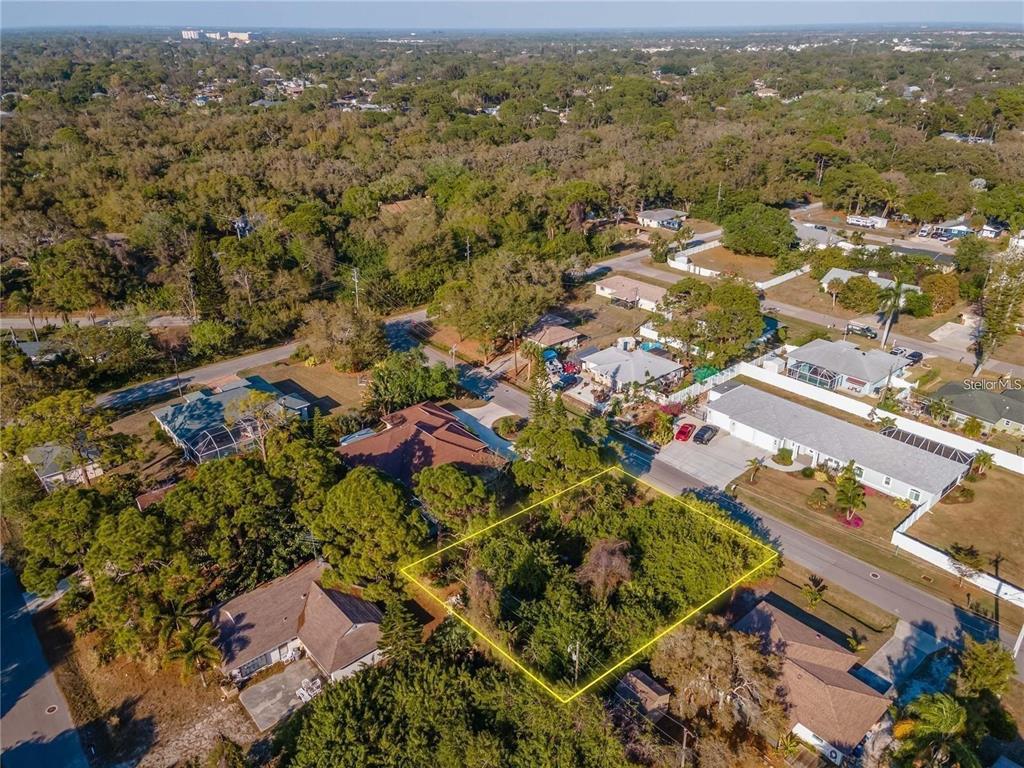 An aerial view shows a vacant, tree-covered residential lot outlined in yellow within a neighborhood — OSPREY ROAD, VENICE, FL