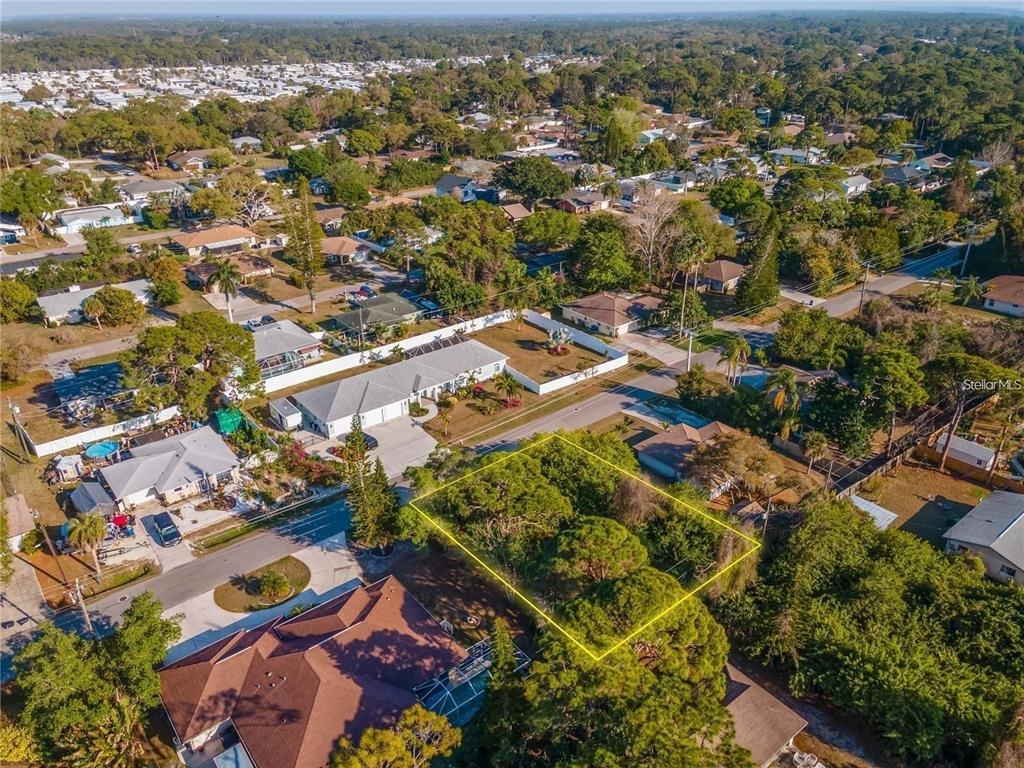 An aerial view shows a vacant, tree-covered residential lot outlined in yellow within a neighborhood — OSPREY ROAD, VENICE, FL