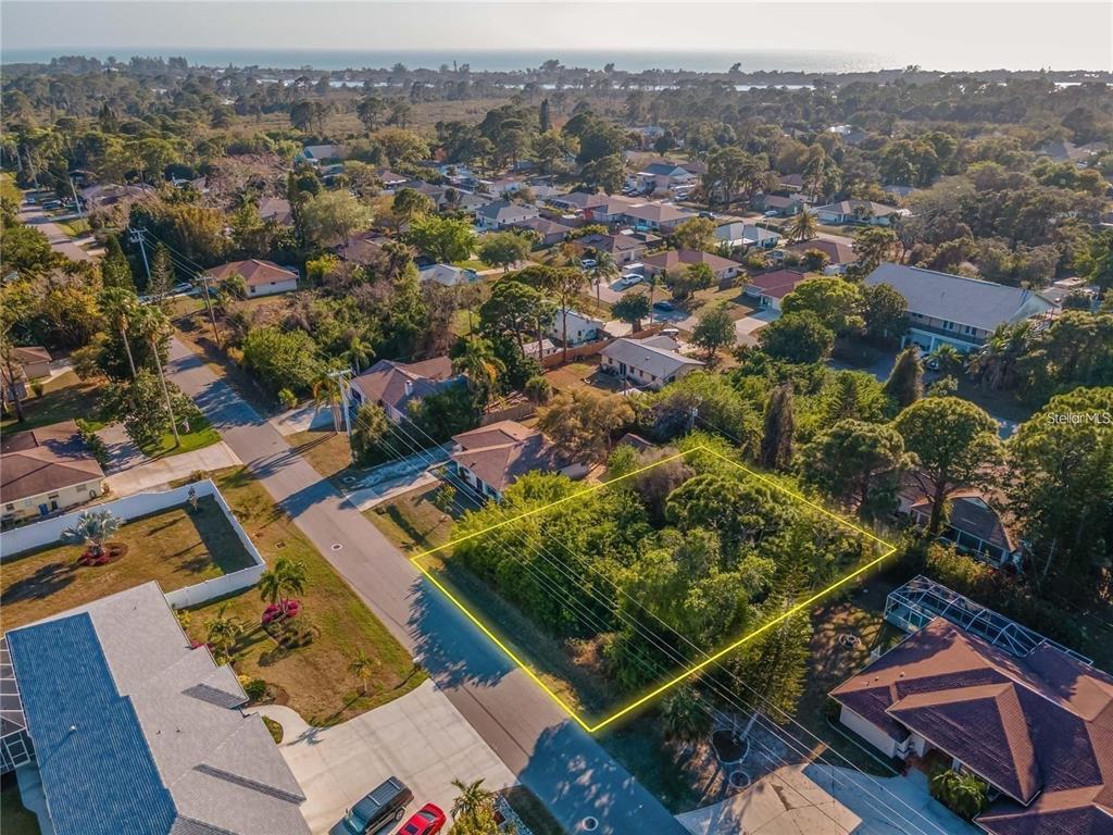 An aerial view shows a vacant, tree-covered residential lot outlined in yellow along a street — OSPREY ROAD, VENICE, FL