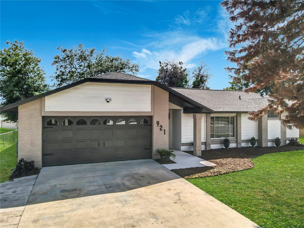 A single-story house with a beige brick and white siding exterior and a two-car garage — 921 FORT SMITH BOULEVARD, DELTONA, FL