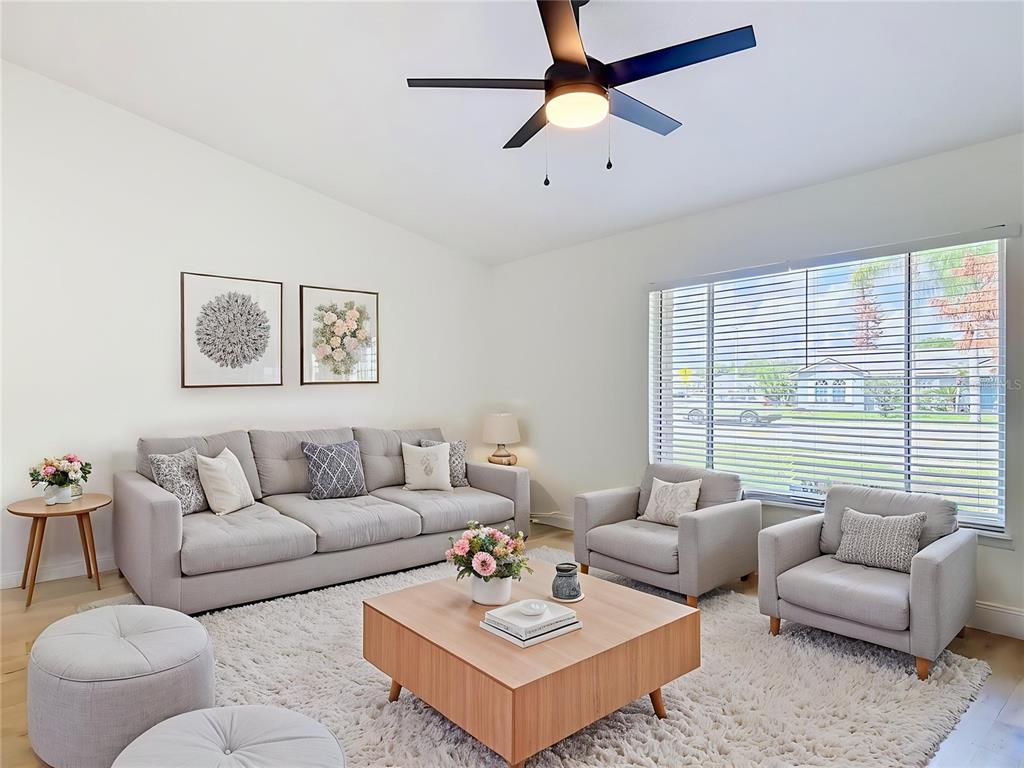 A living room features a grey sofa, two armchairs, a coffee table, and a ceiling fan — 921 FORT SMITH BOULEVARD, DELTONA, FL
