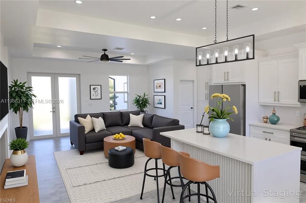 A modern open-concept living room and kitchen featuring a gray sectional sofa and island seating — 114 PRESTON ST, Lehigh Acres FL 33974, LEHIGH ACRES, FL