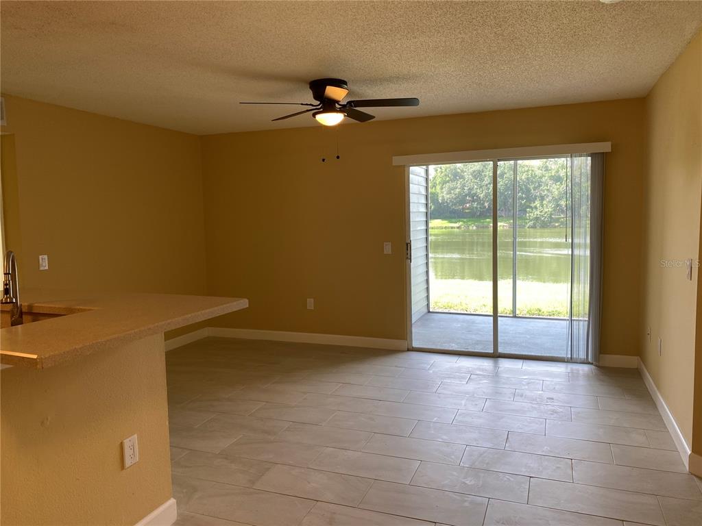 A dining area with tile flooring, a ceiling fan, and sliding doors leading to a patio — 1225 BERMUDA LAKES LANE UNIT 107, KISSIMMEE, FL