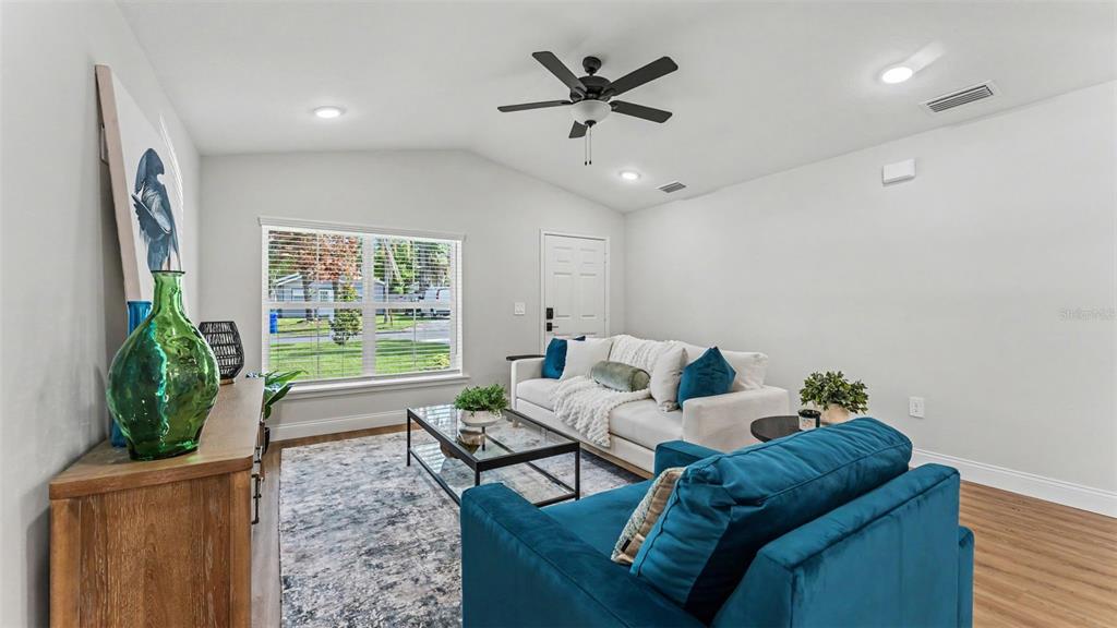 A living room features a white sofa, a teal armchair, and a glass coffee table — 1242 DOROTHY STREET, LAKELAND, FL