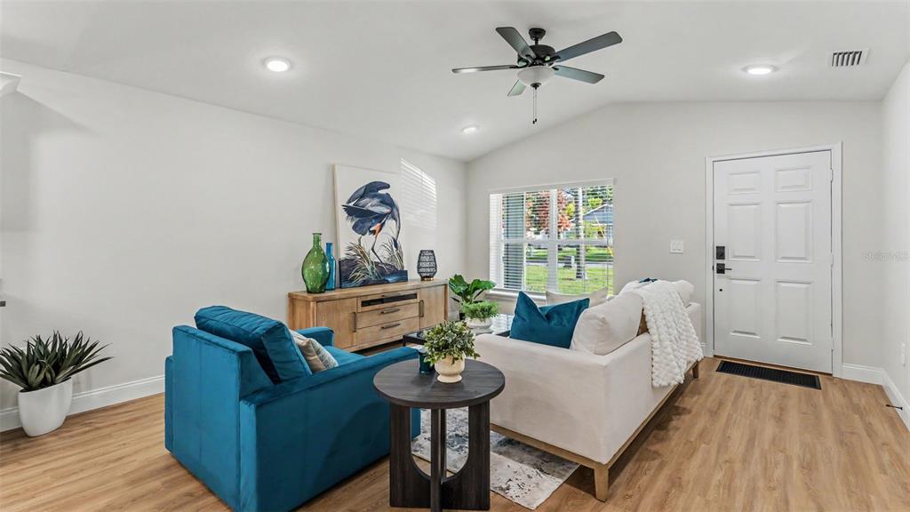 A living room features a white sofa, a blue armchair, wood flooring, and a ceiling fan — 1242 DOROTHY STREET, LAKELAND, FL