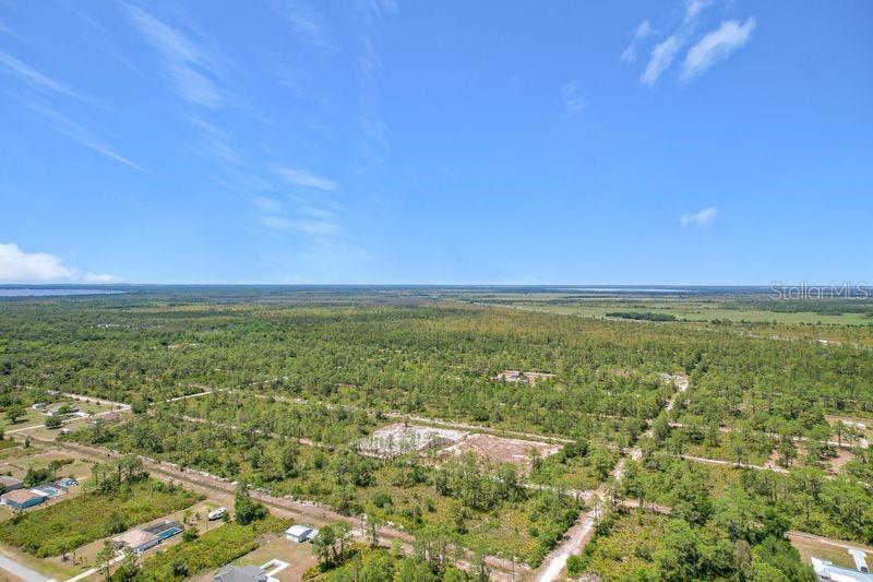 An aerial view shows a large, undeveloped wooded lot with sparse vegetation and nearby houses — 0 EL DORADO DRIVE, INDIAN LAKE ESTATES, FL