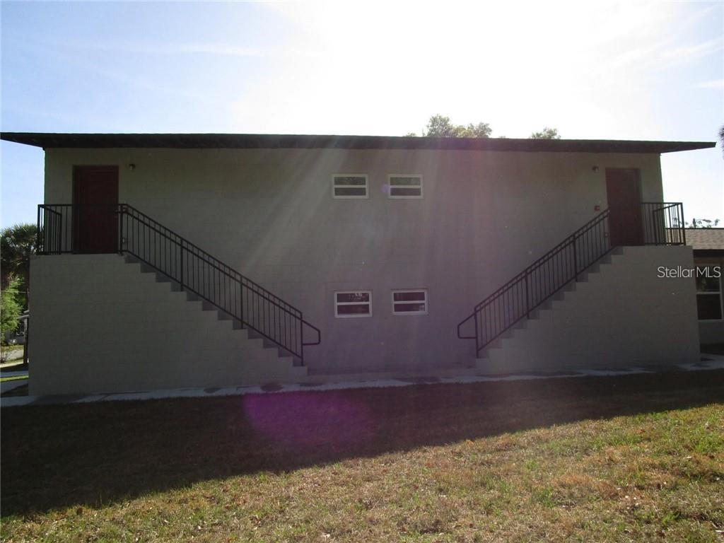 The exterior of a two-story apartment building features two symmetrical staircases leading to upper-level doors — 1002 E MCDONALD AVENUE UNIT 3, EUSTIS, FL