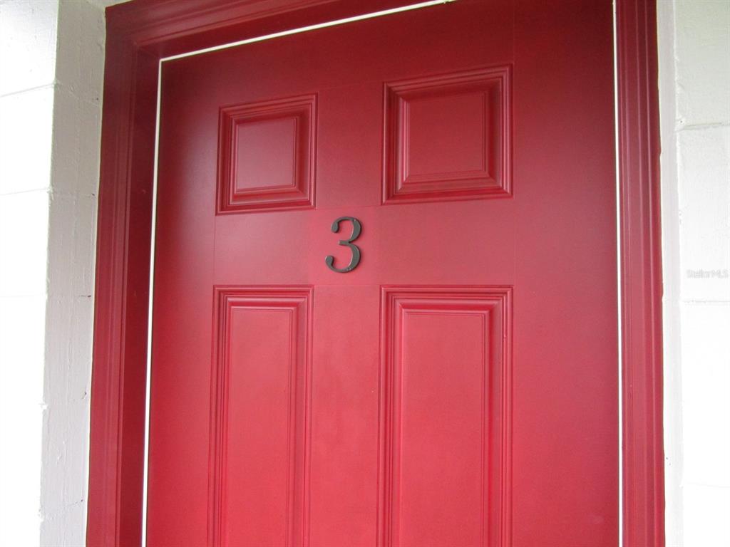 A red front door with four panels and the number three mounted in the center — 1002 E MCDONALD AVENUE UNIT 3, EUSTIS, FL