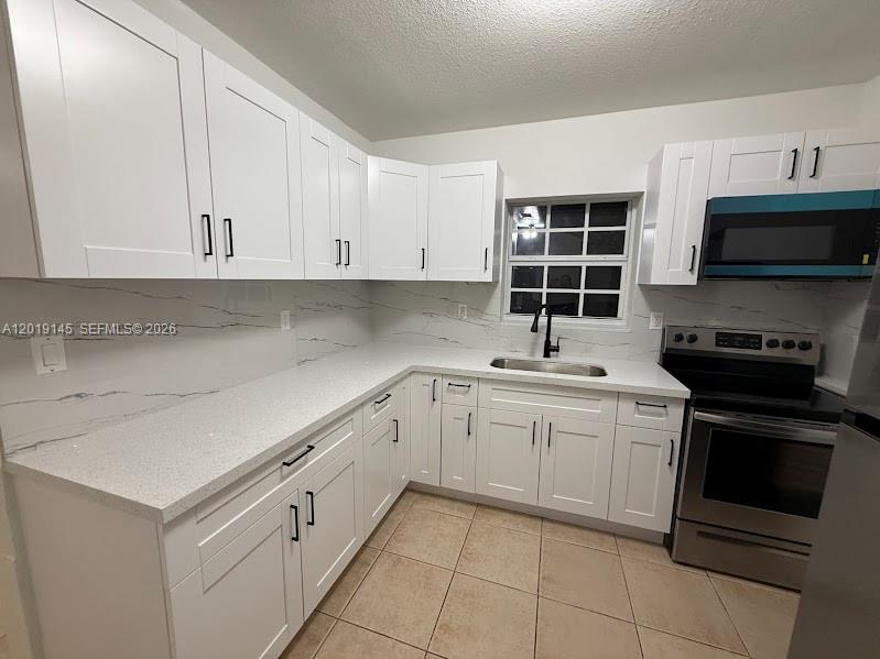 A kitchen features white shaker cabinets, quartz countertops, a marble-patterned backsplash, and stainless steel appliances — 2345 NW 65th St, Miami FL 33147, MIAMI, FL