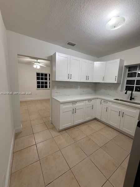 A kitchen with white cabinets, light countertops, and tiled floors, viewed from an adjacent room — 2345 NW 65th St, Miami FL 33147, MIAMI, FL