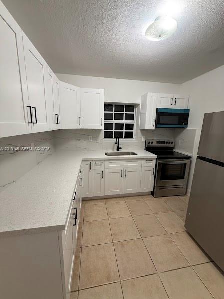 A kitchen with white cabinets, quartz countertops, stainless steel appliances, and light-colored tile flooring — 2345 NW 65th St, Miami FL 33147, MIAMI, FL