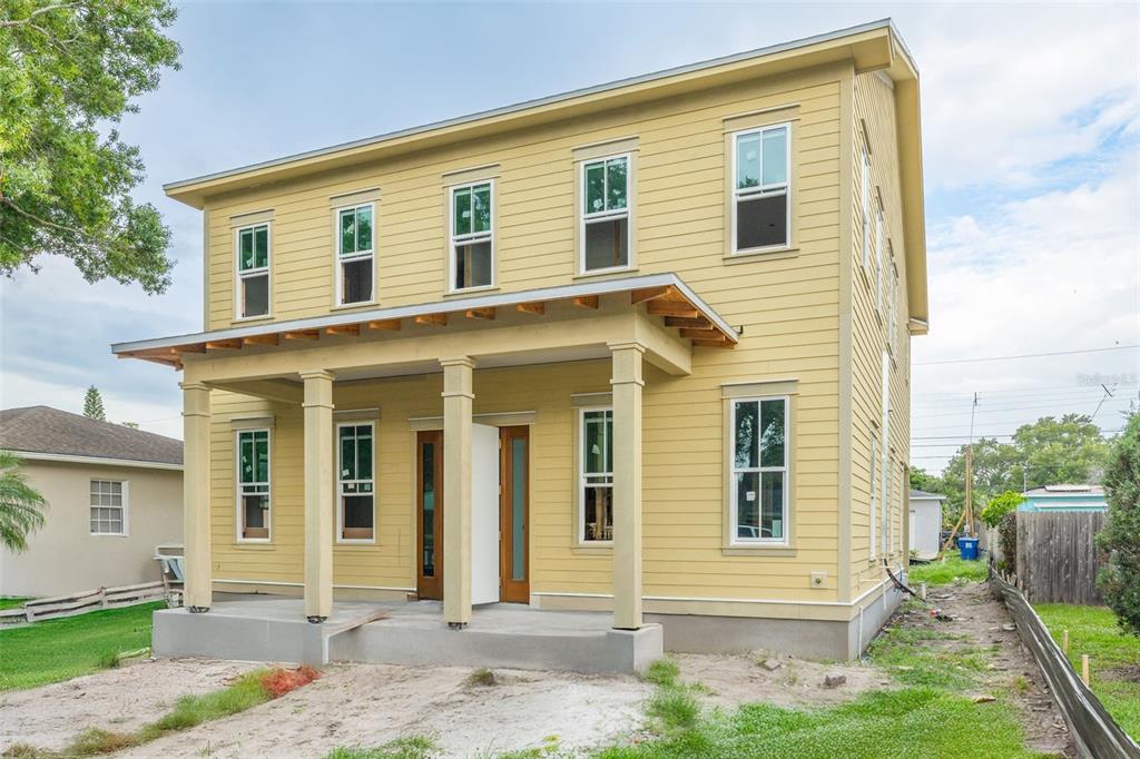 A two-story yellow house with a front porch and multiple windows under a cloudy sky — 3320 15TH STREET N, ST PETERSBURG, FL