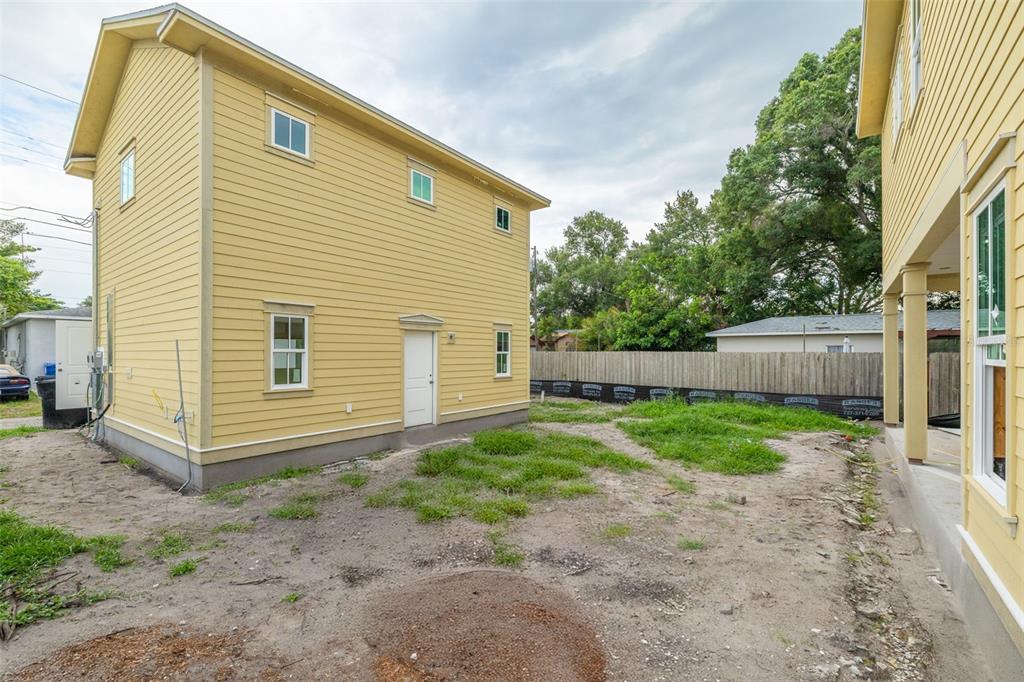 A yellow two-story house exterior stands next to a dirt yard and a wooden fence — 3320 15TH STREET N, ST PETERSBURG, FL