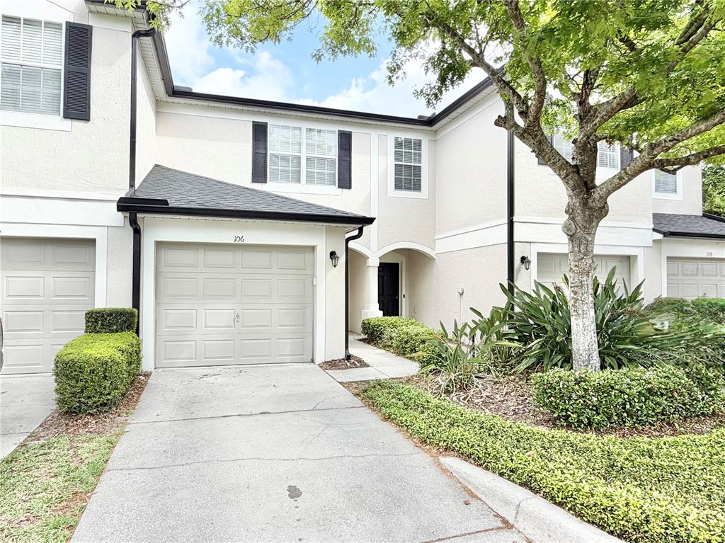 A two-story townhouse exterior features a beige facade, a single-car garage, and a concrete driveway — 6001 TWAIN STREET UNIT 106, ORLANDO, FL