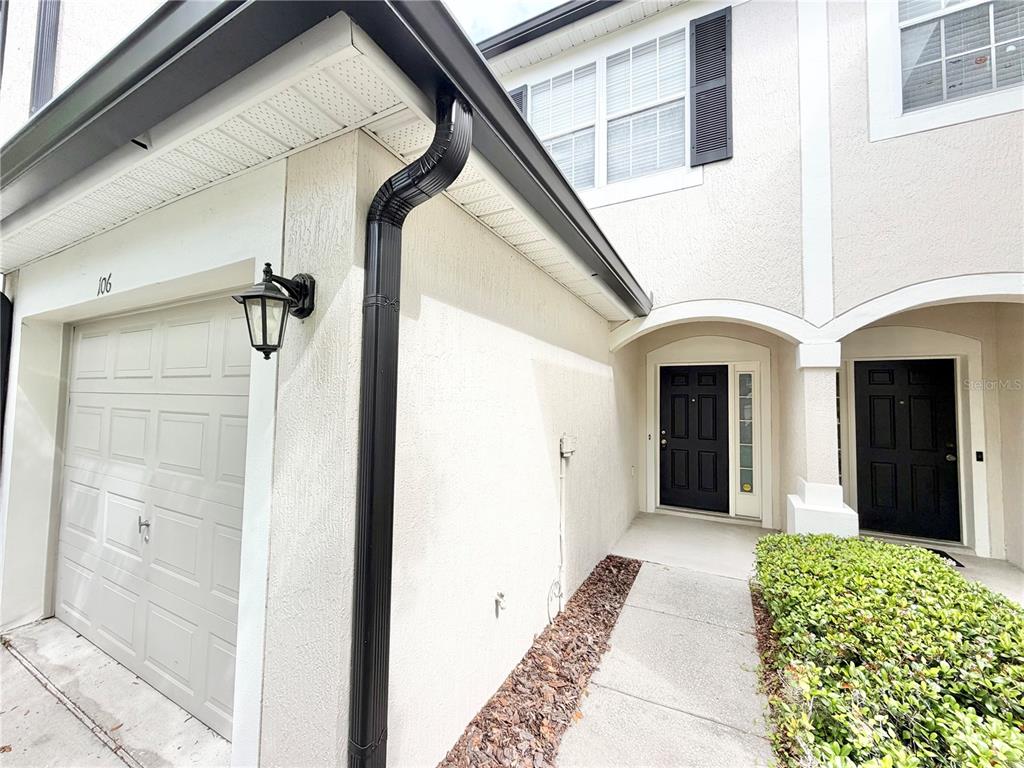 The exterior of a two-story townhouse features a garage, a walkway, and two front doors — 6001 TWAIN STREET UNIT 106, ORLANDO, FL