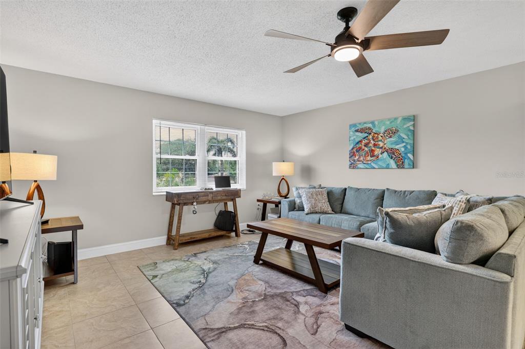 A living room features a sectional sofa, a coffee table, a desk, and a ceiling fan — 1706 BELLEAIR FOREST DRIVE UNIT 220, BELLEAIR, FL