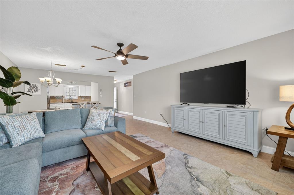 A living room features a blue sectional sofa, a wooden coffee table, and a television console — 1706 BELLEAIR FOREST DRIVE UNIT 220, BELLEAIR, FL
