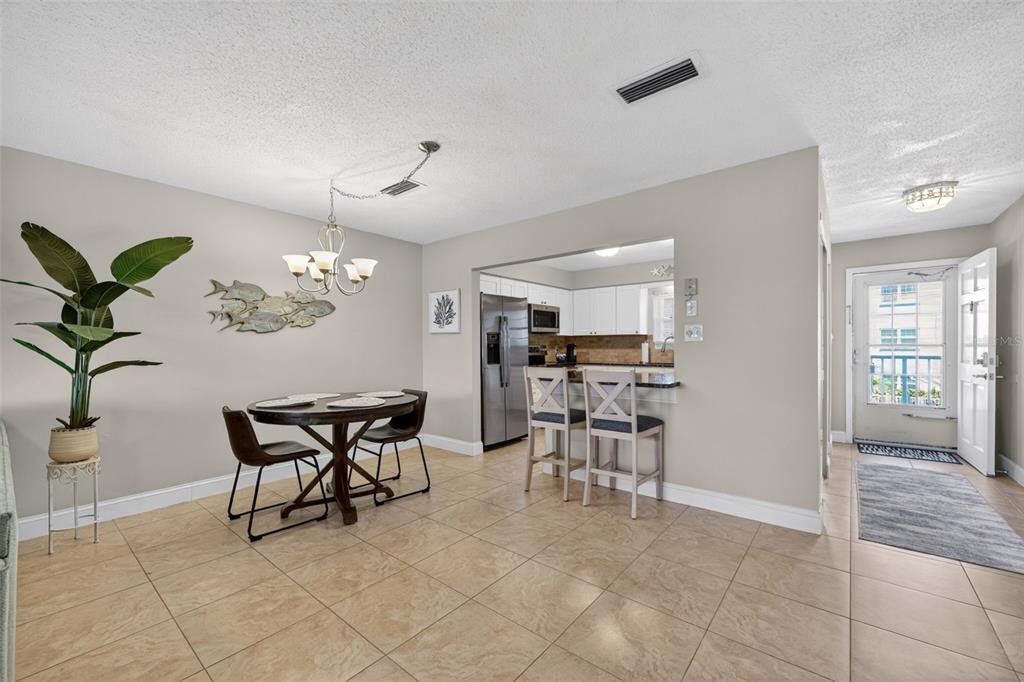 A dining area with tile floors, a round table, and an open kitchen with bar seating — 1706 BELLEAIR FOREST DRIVE UNIT 220, BELLEAIR, FL