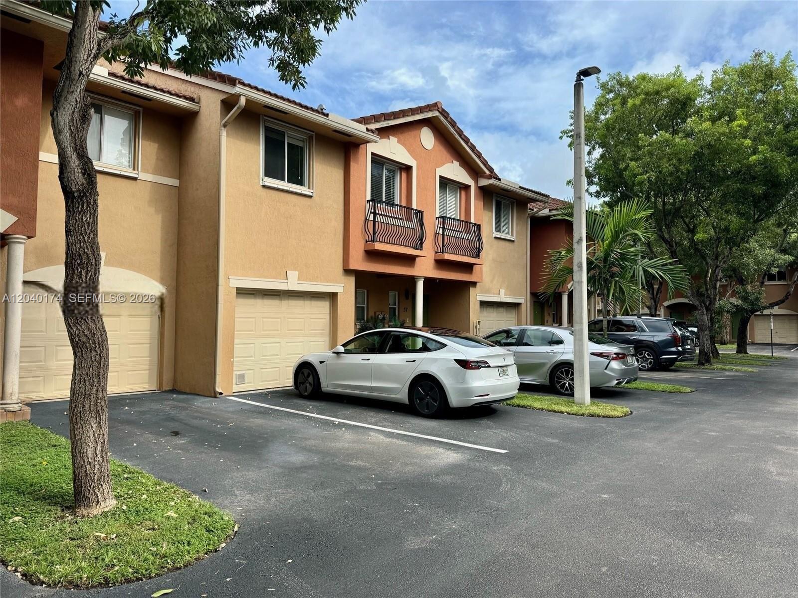 An exterior view of a two-story townhouse complex with a parking area and parked cars — 31 SE 3, Hallandale Beach FL 33009, HALLANDALE BEACH, FL