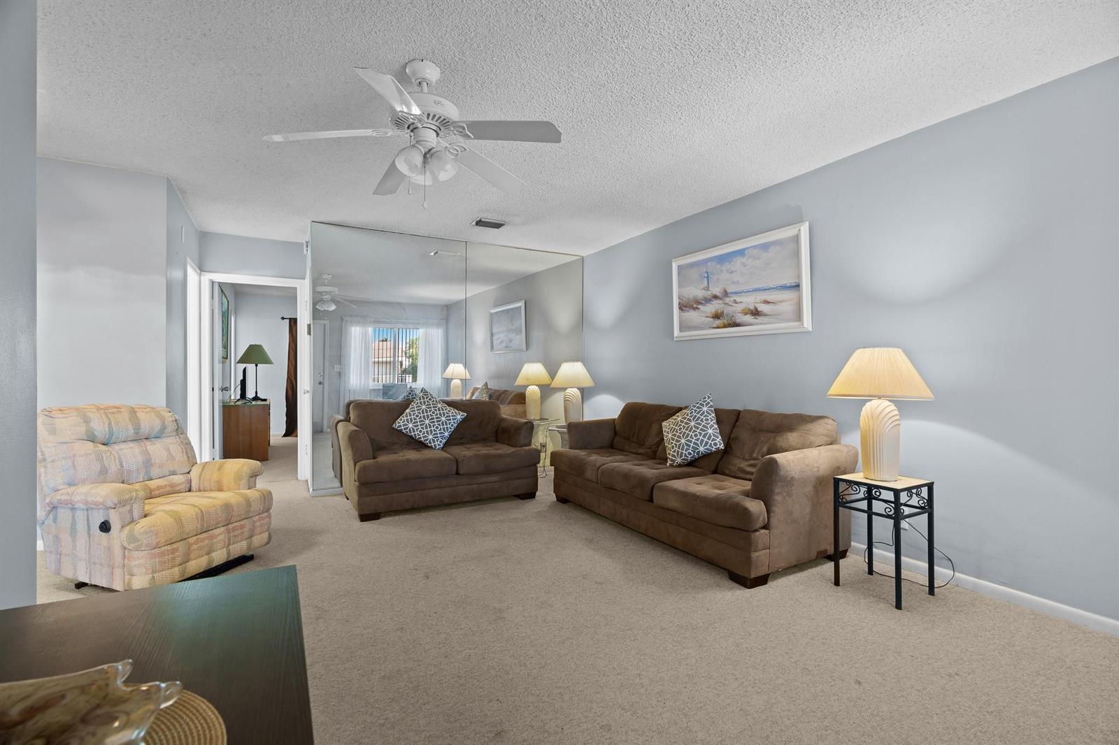 A living room features beige carpet, a mirrored wall, two brown sofas, and a recliner — 2100 NE 38th Street # 243, Lighthouse Point FL 33064, LIGHTHOUSE POINT, FL