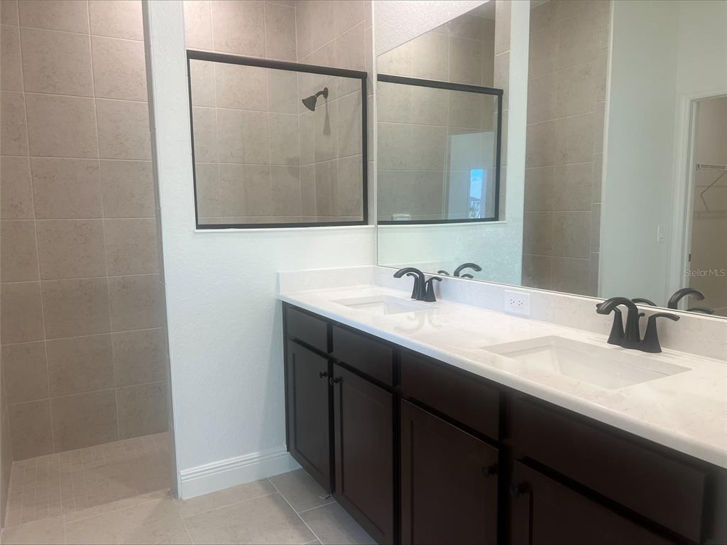 A bathroom features a double vanity with dark cabinets, white countertops, and a tiled shower — 1382 SHIELDS STREET, PORT CHARLOTTE, FL