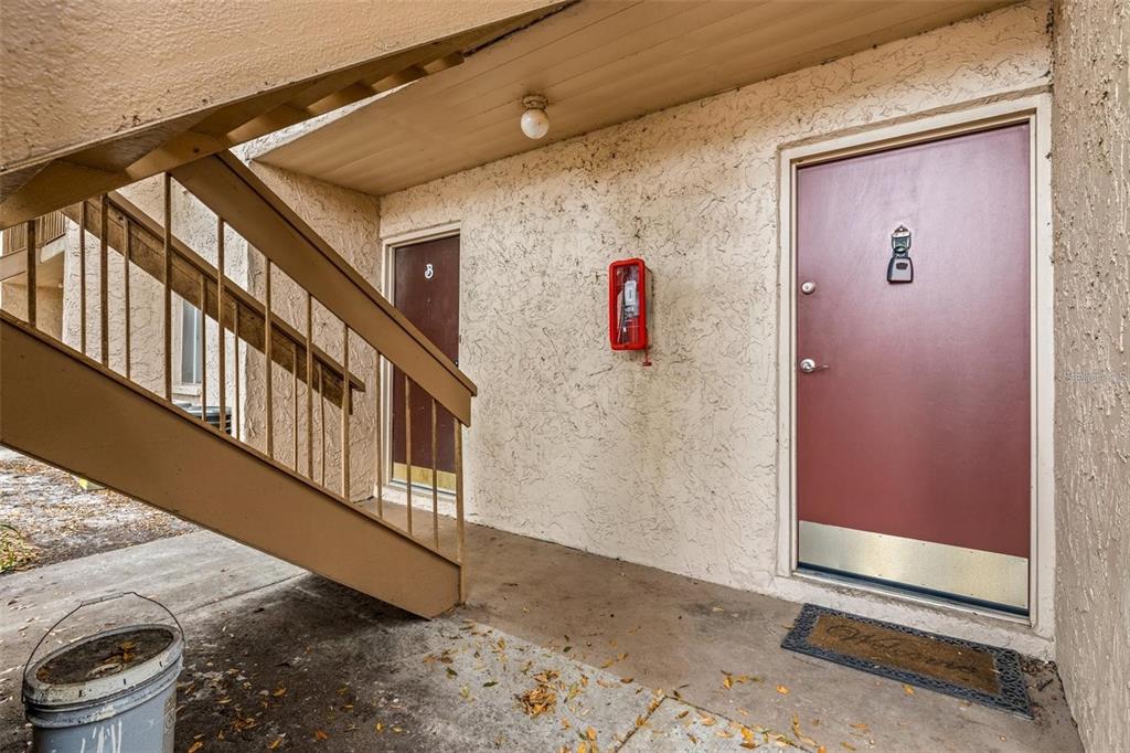 An exterior view of an apartment building entrance with two doors, stairs, and a fire extinguisher — 7510 PRESLEY PLACE UNIT 98-A, TAMPA, FL