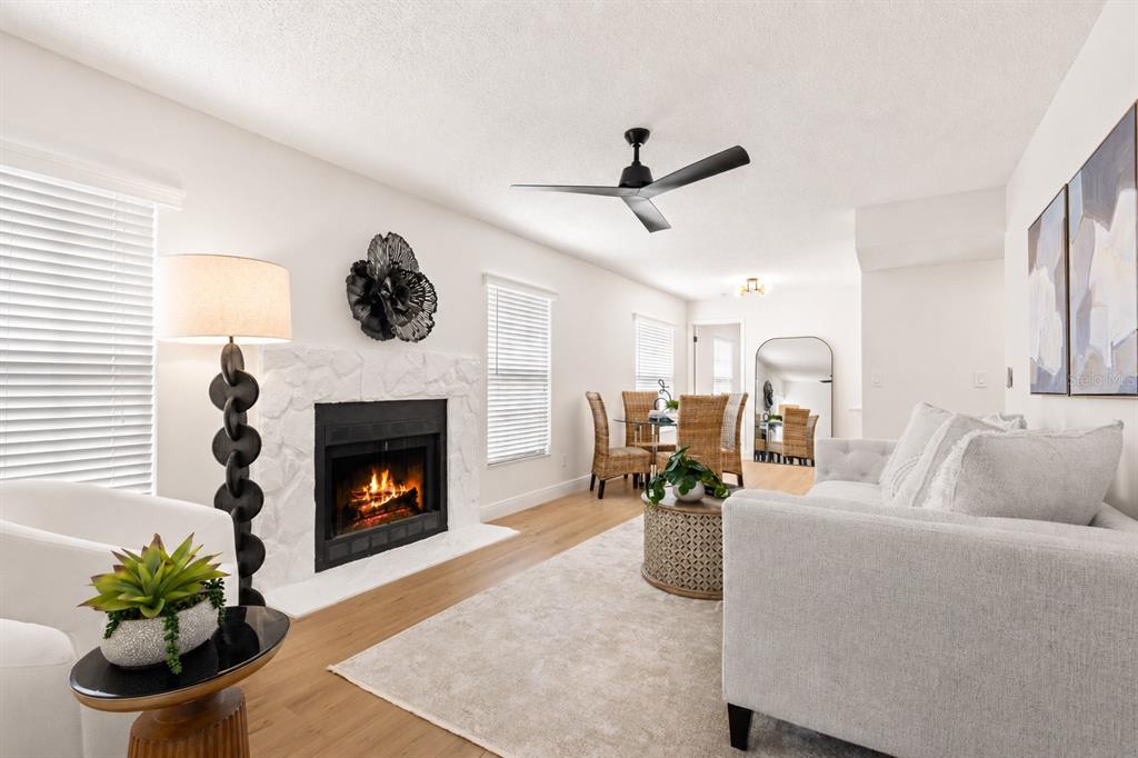 A living room features a white stone fireplace, light wood flooring, and a dining area — 2981 BONAVENTURE CIRCLE UNIT 202, PALM HARBOR, FL