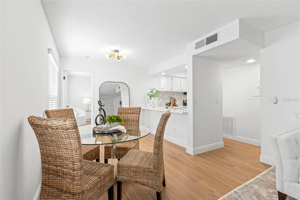 A dining area with a glass table and wicker chairs sits next to a kitchen — 2981 BONAVENTURE CIRCLE UNIT 202, PALM HARBOR, FL