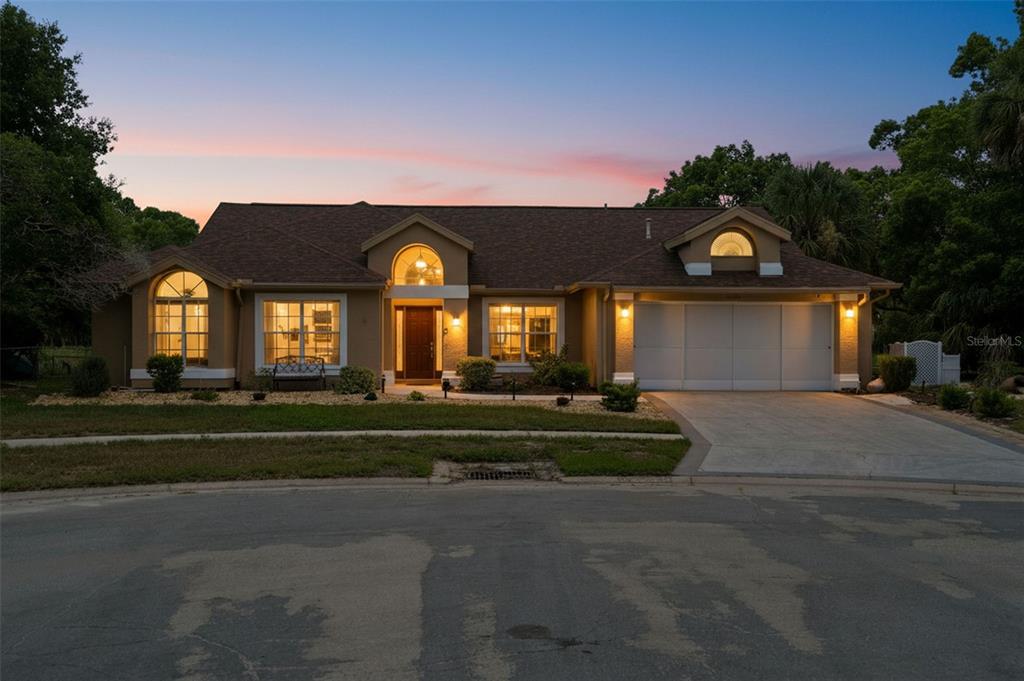 A single-story house with a brown roof, tan stucco exterior, and a two-car garage — 10296 WINDSOR COURT, SPRING HILL, FL