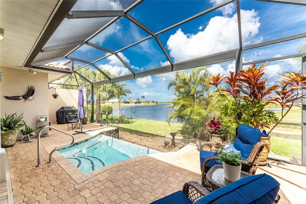 A screened-in patio features a small pool, brick pavers, and a view of a lake — 16237 CAPE HORN BOULEVARD, PUNTA GORDA, FL