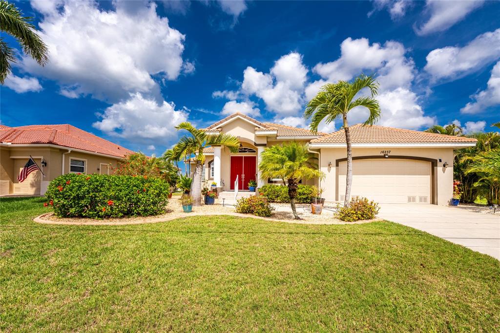 A single-story house with a beige stucco exterior, red front doors, and a two-car garage — 16237 CAPE HORN BOULEVARD, PUNTA GORDA, FL